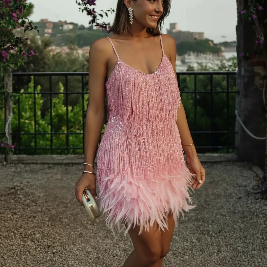 A woman wearing a pink dress with tassel stitching, feather embellishments, and sequins, featuring a sleeveless design and a pencil skirt.