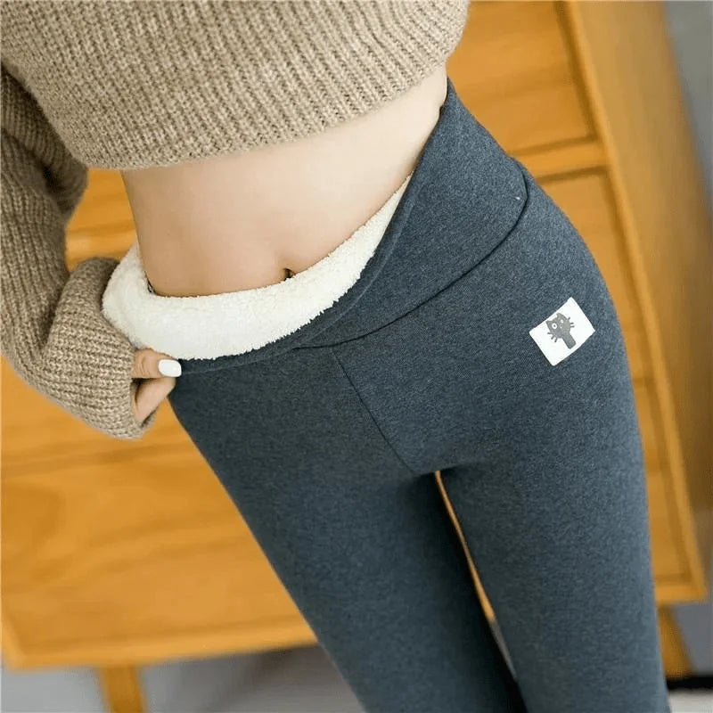 A pair of beige fleece-lined leggings with a gray waistband. The image shows the leggings worn by a person sitting, focusing on the texture and fit around the knees.