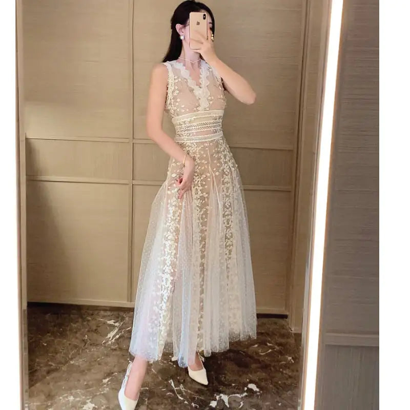 A model wearing a white mesh embroidered waistband dress with a V-neck collar and floral patterns.
