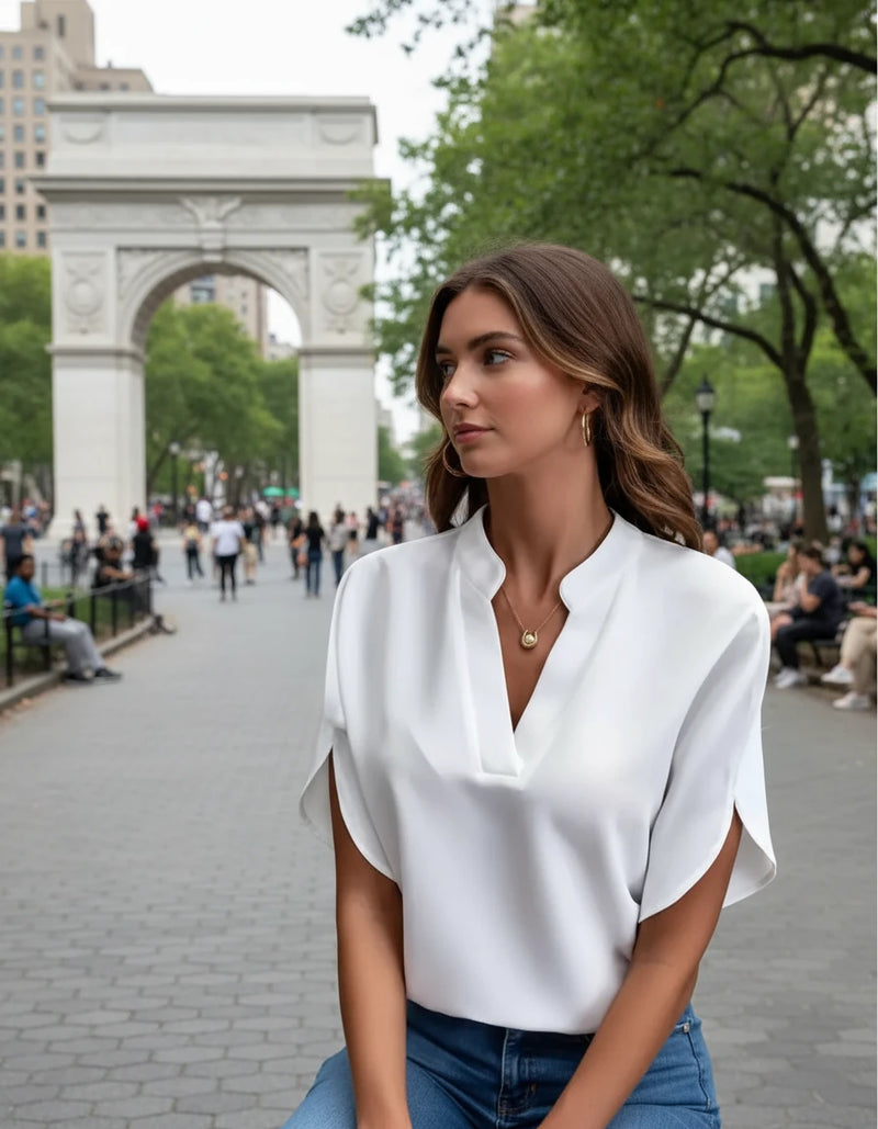 A woman wearing a green V-neck chiffon shirt with short sleeves, paired with blue jeans.