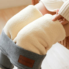 A pair of beige fleece-lined leggings with a gray waistband, branded with a tag that reads 'FASHION'. The image shows the leggings worn by a person sitting, focusing on the texture and fit around the knees.