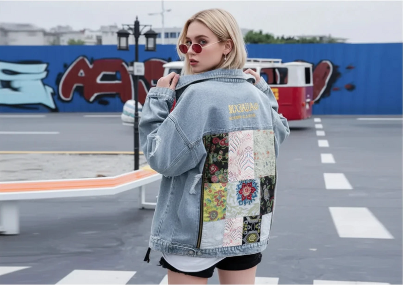 Person wearing a patchwork denim jacket with colorful patterns in an outdoor setting.