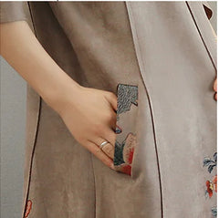 Person wearing a beige coat with a decorative pocket flap