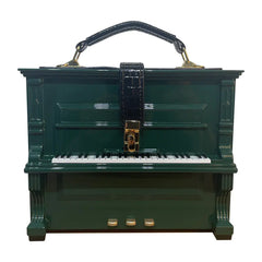 Green piano-shaped handbag with a black strap on a white background