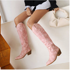 Person wearing pink knee-high boots sitting on a white couch.