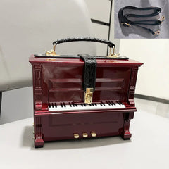 Red piano-shaped handbag with black strap on a white surface