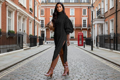 Woman wearing a black knit dress with a high slit and knee-high boots 