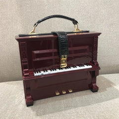 Piano-shaped handbag with a strap on a textured surface