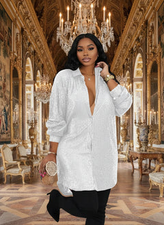 A woman wearing a long sleeve, allover sequin shirt dress in white color with a V-neck.