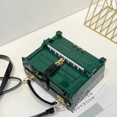 Green handbag with black strap on a white surface