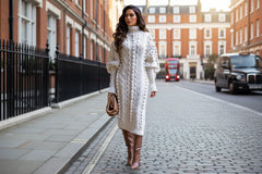 Woman wearing a white cable knit sweater dress with brown boots 