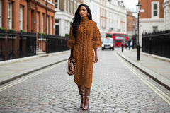 Woman wearing a brown cable knit dress with matching boots on a white background