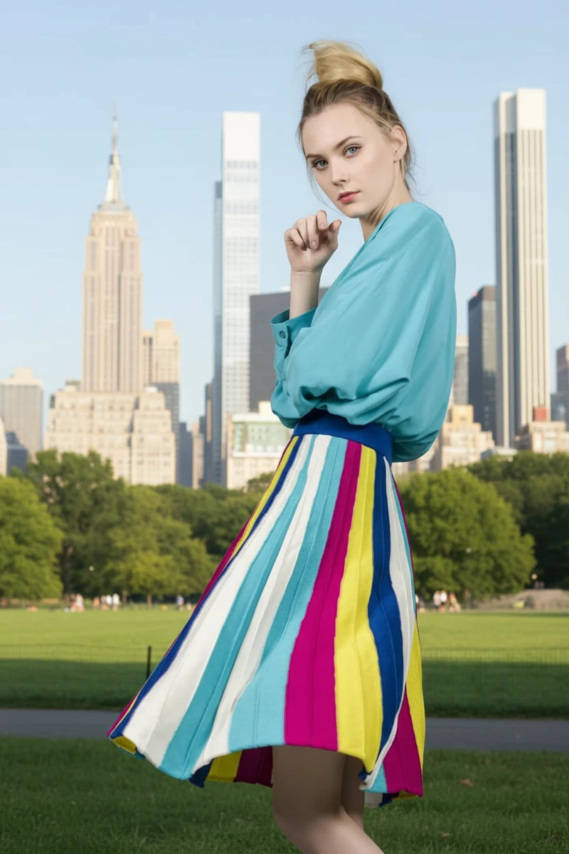 Woman wearing a colorful striped skirt and blue top on a gray background
