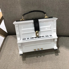 Piano-shaped handbag on a textured surface with a neutral background