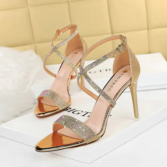 A pair of Gold rhinestone-embellished sandals with an open toe and ankle strap.