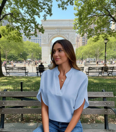 A woman wearing a light blue V-neck chiffon shirt with short sleeves, paired with blue jeans.