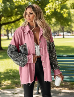 A woman wearing a pink plaid long-sleeve jacket with sequin detailing on the sleeves, paired with a white top and black pants.