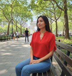 A woman wearing a red V-neck chiffon shirt with short sleeves, paired with blue jeans.