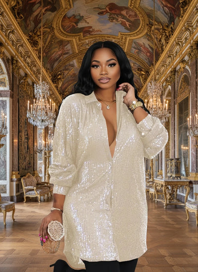 A woman wearing a long sleeve, allover sequin shirt dress in beige color with a V-neck.