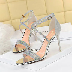 A pair of Silver rhinestone-embellished sandals with an open toe and ankle strap.