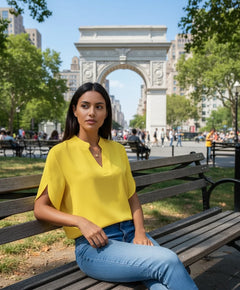 A woman wearing a yellow V-neck chiffon shirt with short sleeves, paired with blue jeans.