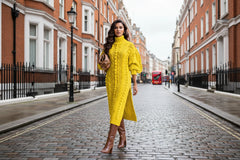 Woman wearing a bright yellow cable knit sweater with a high slit.